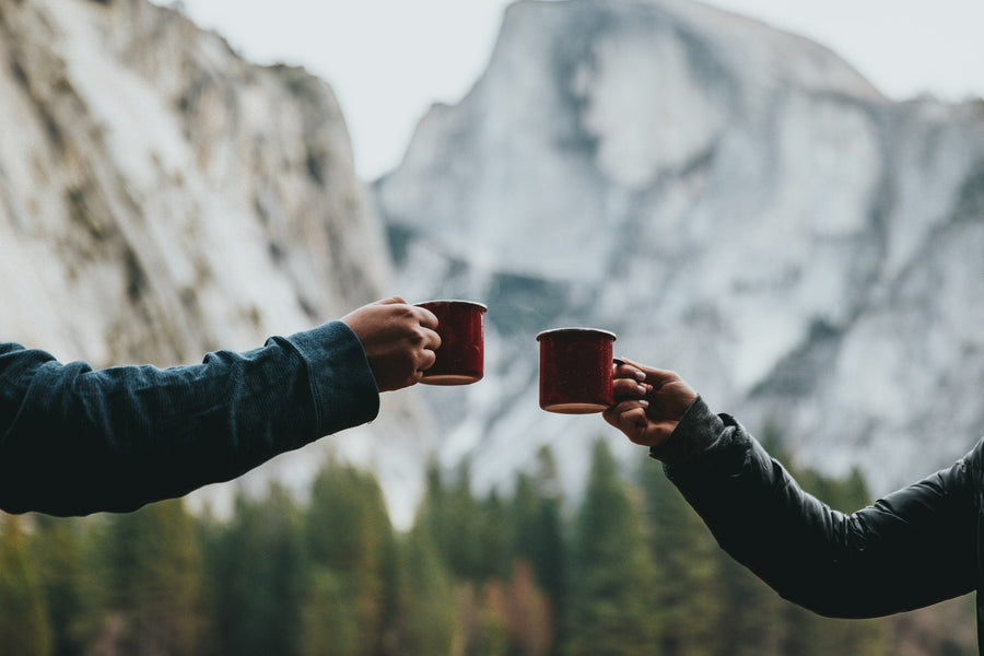 Two mugs of fresh drip coffee held up in a toast.