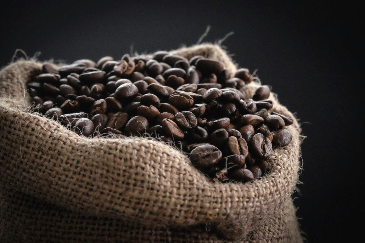 Whole roasted coffee beans in a burlap sack