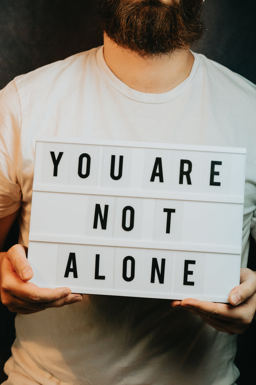 Person holding a sign that says you are not alone